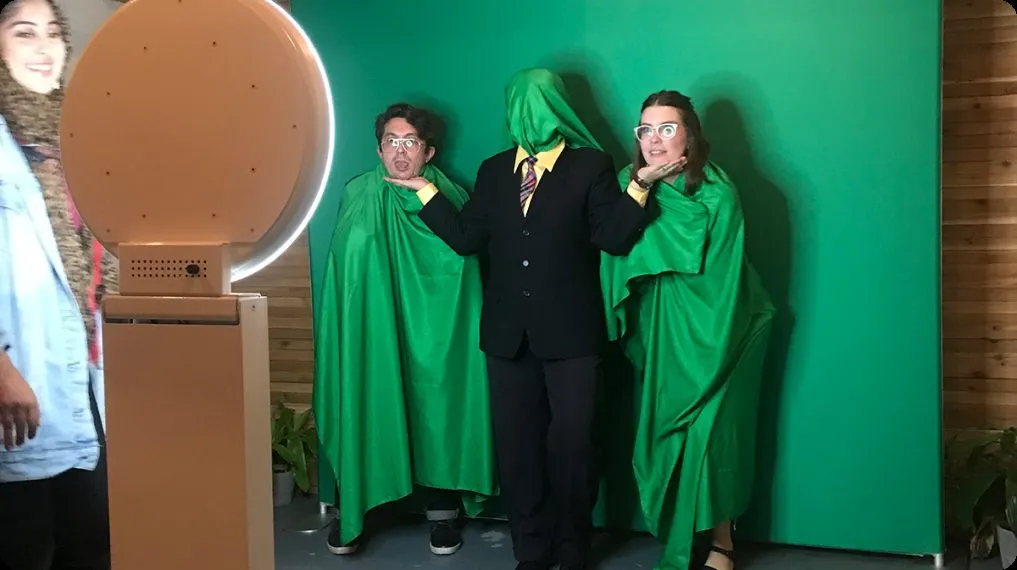 Guest at a green screen photo booth 'Tap to Start' screen at a DMV event.