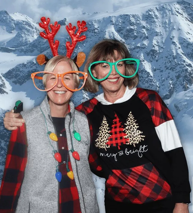Two guests posing in front of the green screen backdrop while the booth captures their shot.
