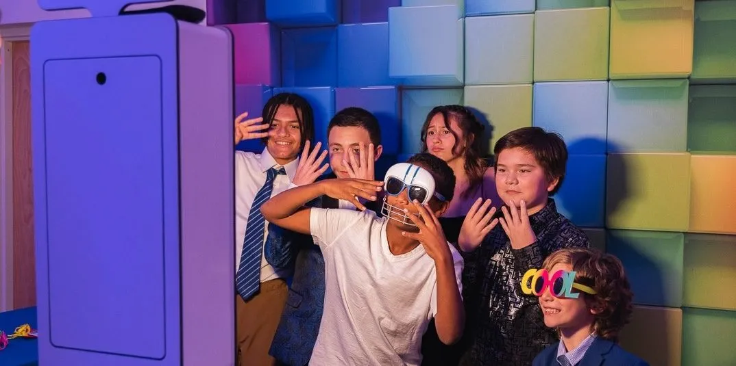 Guests posing together in front of a print photo booth backdrop at a Baltimore party.