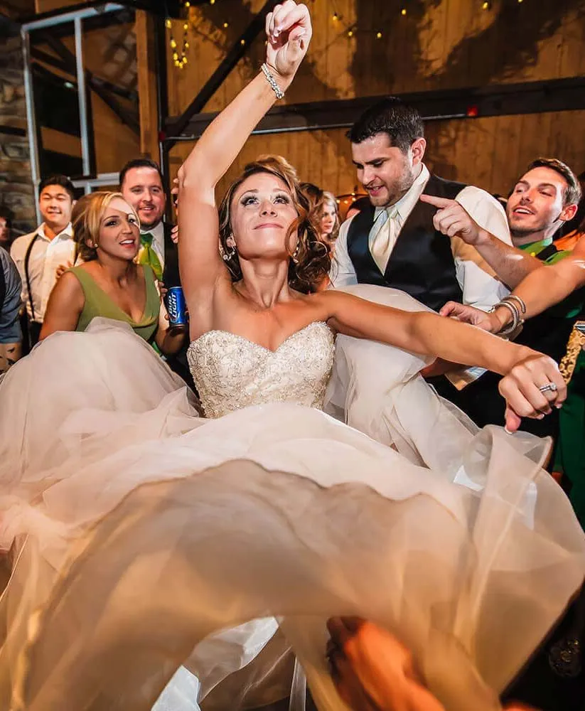 Bride and groom dancing together on a crowded reception dance floor.